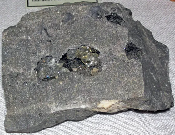 A slab of gray dolostone with a cavity holding clear quartz crystals