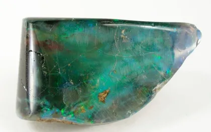 A polished dark opal with green and blue flashes of color